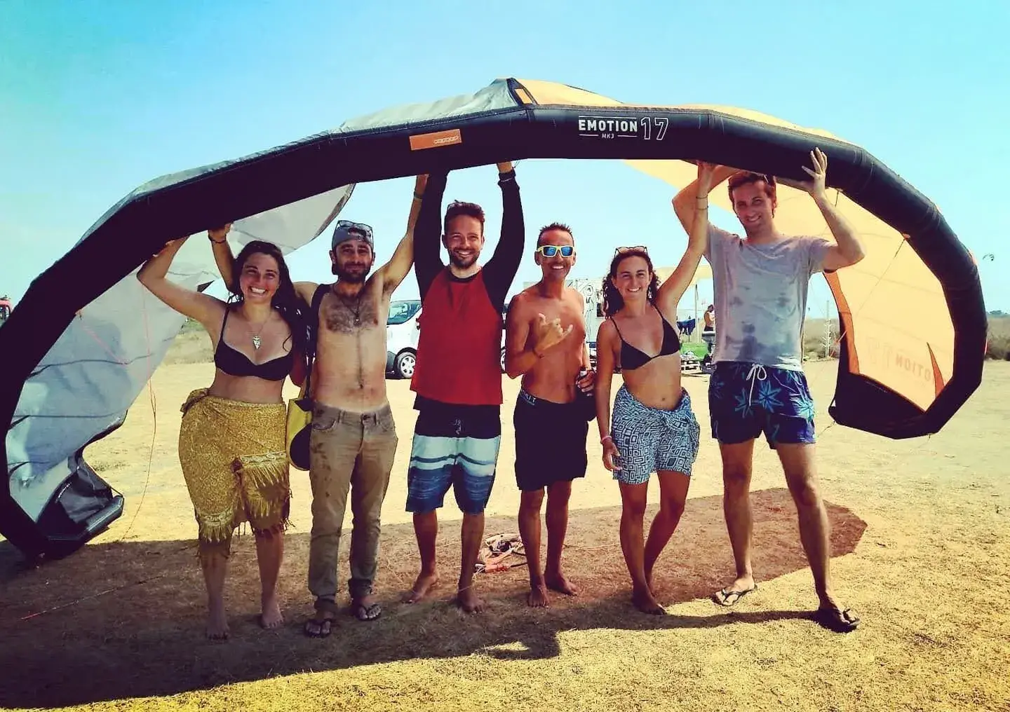 Group of kitesurf students laughing together on the beach